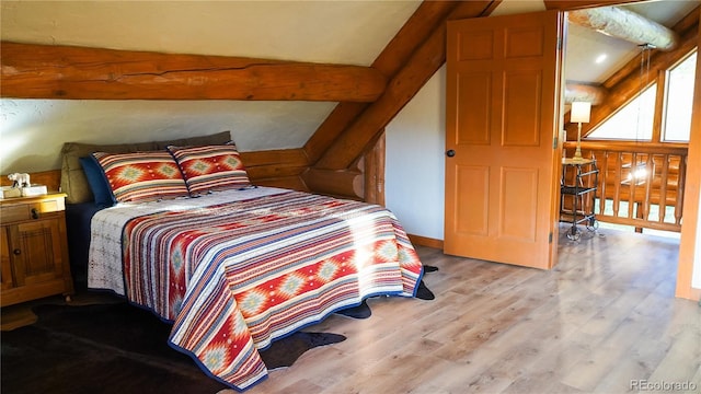bedroom with lofted ceiling with beams and wood finished floors
