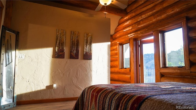 bedroom with wood-type flooring, ceiling fan, and rustic walls