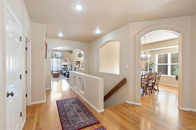 hall featuring plenty of natural light, light hardwood / wood-style floors, and a notable chandelier