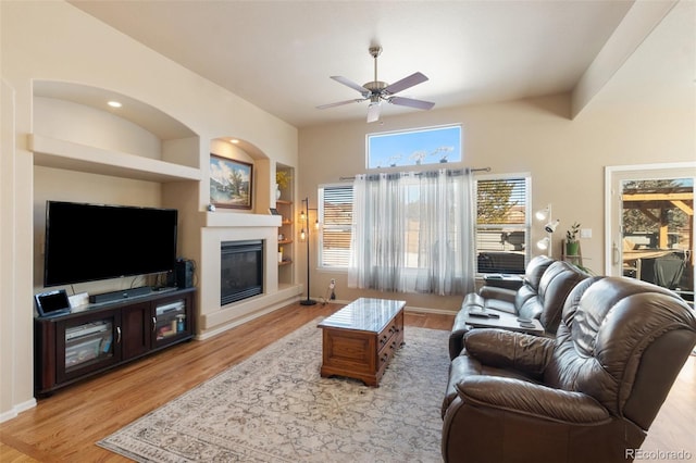 living room featuring ceiling fan, light wood-type flooring, and built in shelves