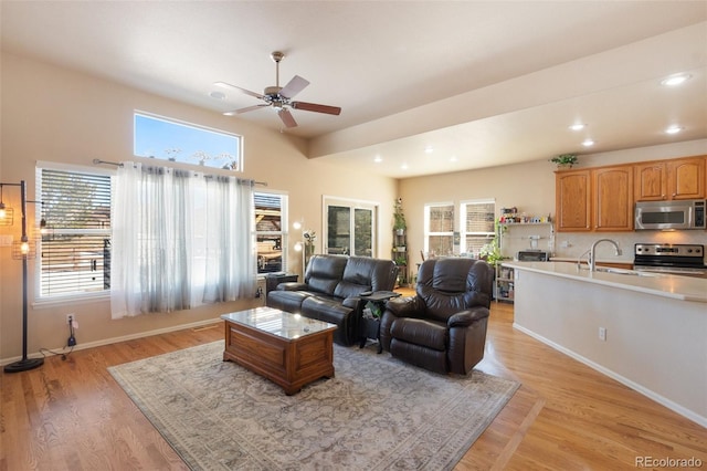 living room featuring ceiling fan, sink, and light wood-type flooring