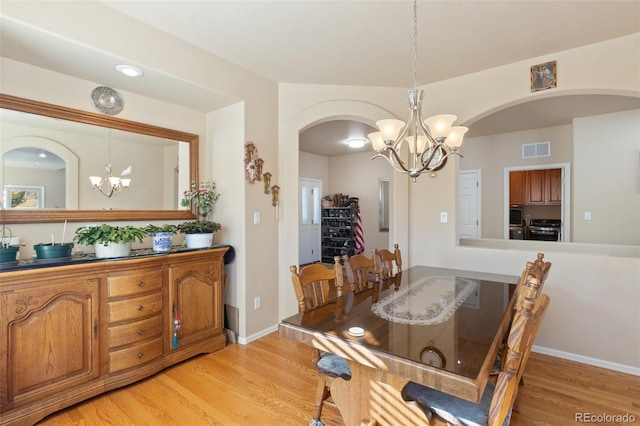 dining space with an inviting chandelier and light hardwood / wood-style flooring