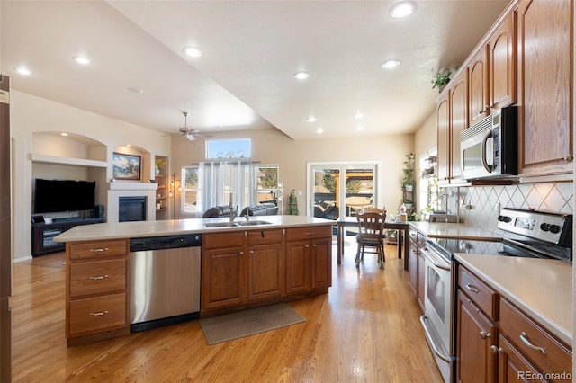 kitchen featuring appliances with stainless steel finishes, tasteful backsplash, sink, ceiling fan, and light hardwood / wood-style flooring