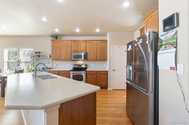 kitchen with an island with sink, appliances with stainless steel finishes, sink, and decorative backsplash