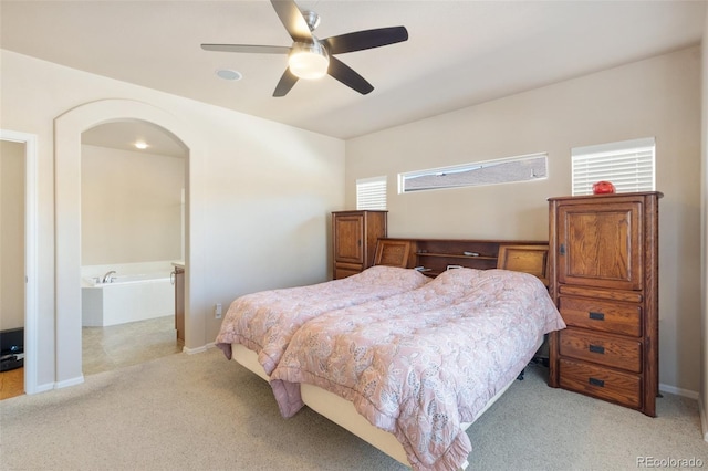 bedroom with connected bathroom, light colored carpet, and ceiling fan