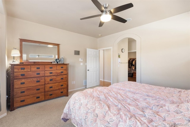 carpeted bedroom featuring ceiling fan, a closet, and a walk in closet