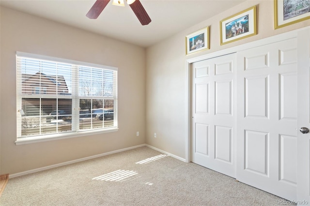 unfurnished bedroom featuring light carpet, a closet, and ceiling fan