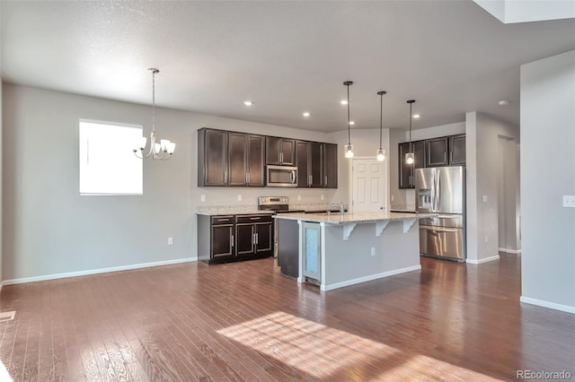 15955 E Otero Cir, Centennial, CO 80112 - kitchen with appliances with stainless steel finishes, dark wood-style floors, a kitchen breakfast bar, a chandelier, and dark brown cabinets