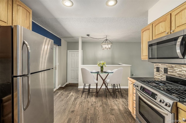 kitchen with a textured ceiling, decorative light fixtures, light brown cabinetry, dark wood-type flooring, and appliances with stainless steel finishes