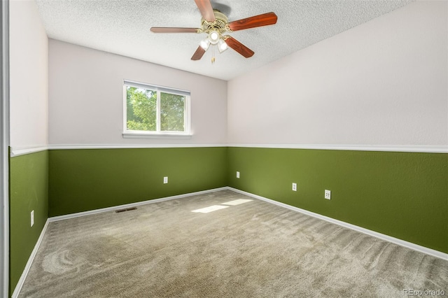 spare room featuring a textured ceiling, ceiling fan, and carpet