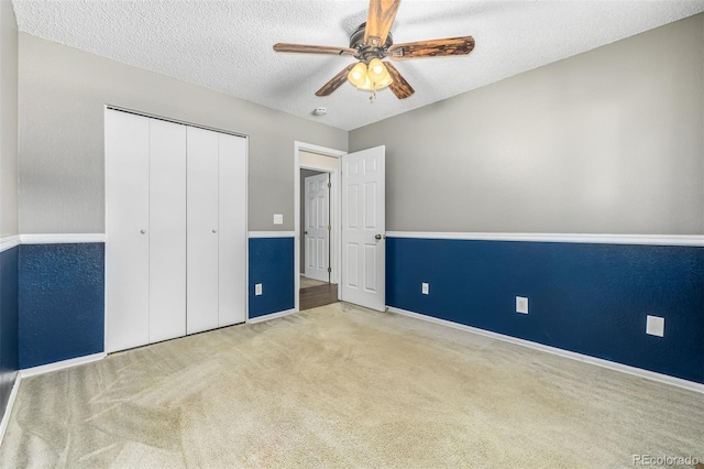 unfurnished bedroom featuring a textured ceiling, ceiling fan, a closet, and carpet floors