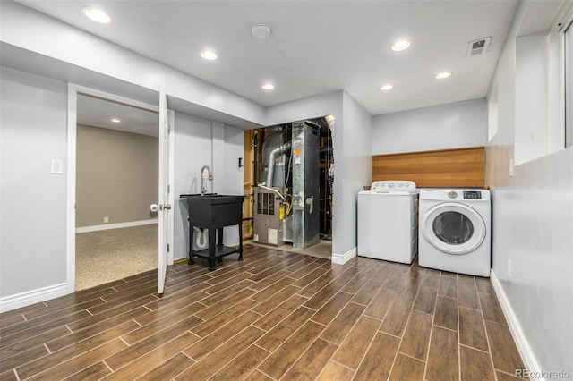 clothes washing area featuring dark hardwood / wood-style floors, heating unit, and separate washer and dryer