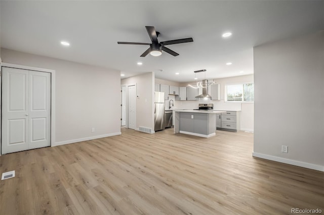 kitchen featuring a center island, stainless steel appliances, light hardwood / wood-style floors, sink, and hanging light fixtures