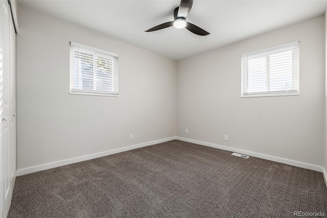 spare room with dark colored carpet and ceiling fan