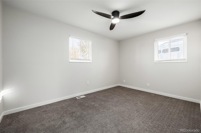 spare room featuring ceiling fan and dark carpet