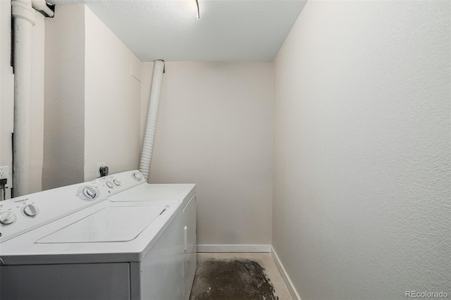 clothes washing area with separate washer and dryer and a textured ceiling