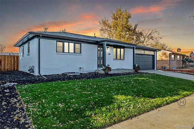 single story home featuring a garage and a lawn