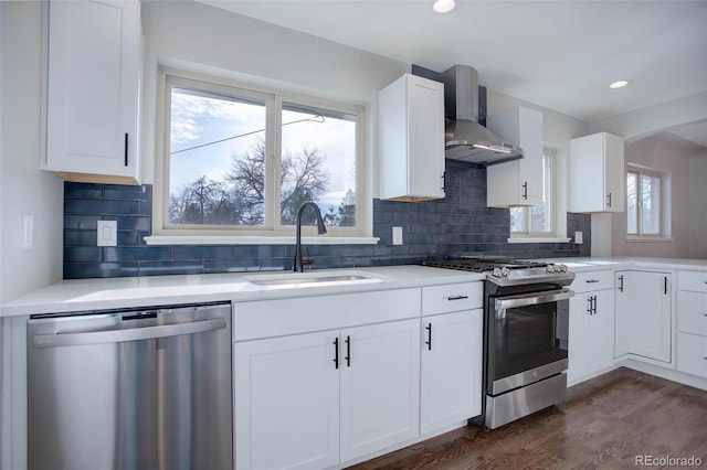 kitchen with dark wood-type flooring, sink, wall chimney exhaust hood, white cabinetry, and stainless steel appliances