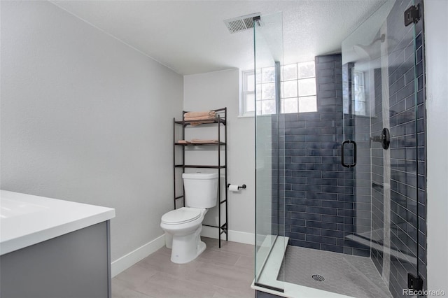 bathroom with a shower with door, vanity, a textured ceiling, and toilet