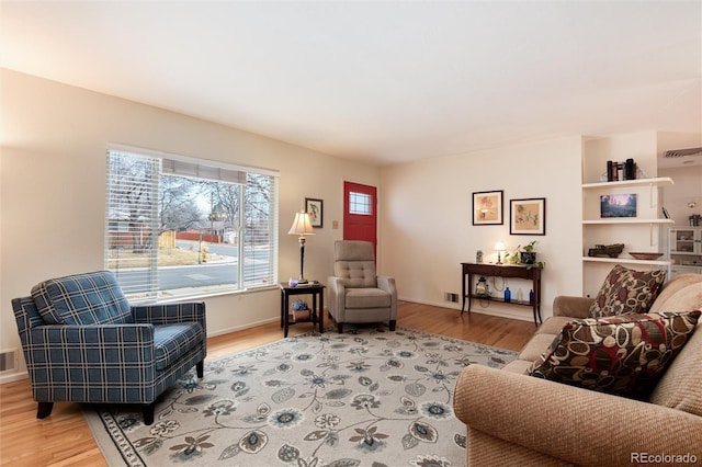 living room featuring visible vents, baseboards, and light wood finished floors