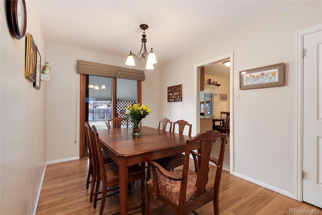 dining room with light wood-style flooring, baseboards, and an inviting chandelier