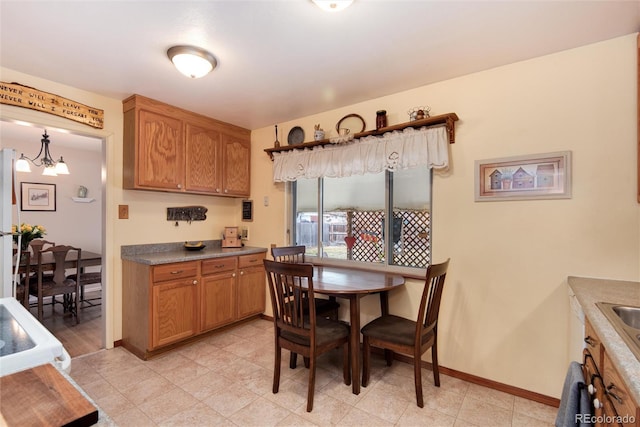 kitchen with baseboards, brown cabinets, and a notable chandelier