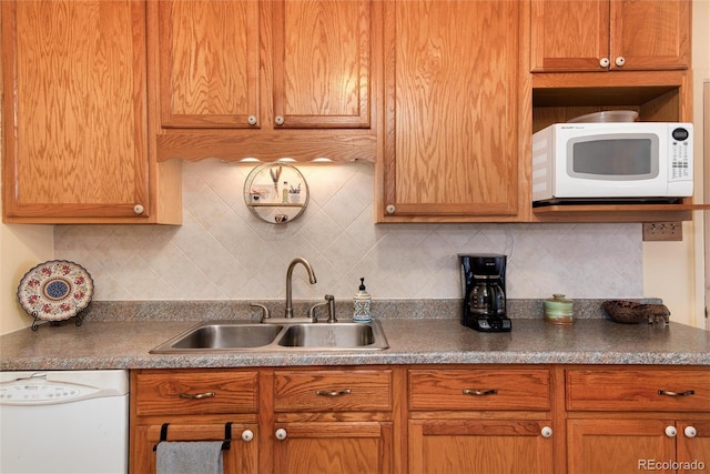 kitchen with a sink, decorative backsplash, white appliances, and brown cabinetry