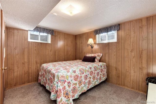 bedroom with carpet flooring, wood walls, and a textured ceiling