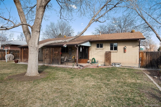 rear view of property with fence, brick siding, a lawn, and entry steps