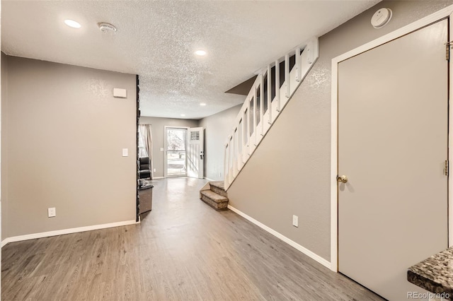 interior space with stairway, wood finished floors, baseboards, recessed lighting, and a textured ceiling