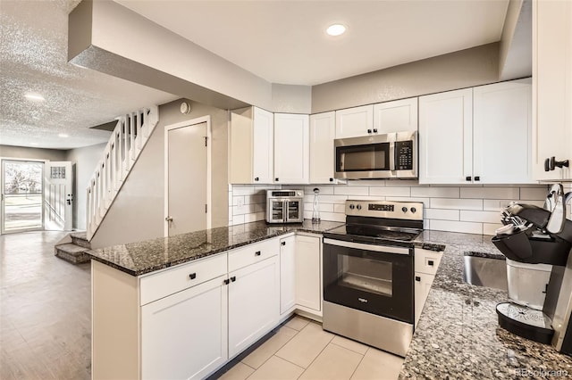 kitchen featuring backsplash, appliances with stainless steel finishes, white cabinetry, and a peninsula