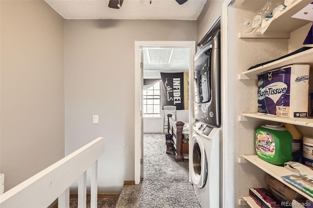 clothes washing area featuring laundry area, a textured ceiling, stacked washer / dryer, carpet flooring, and a textured wall