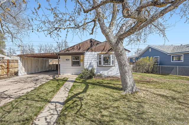 back of property with concrete driveway, an attached carport, fence, and a lawn