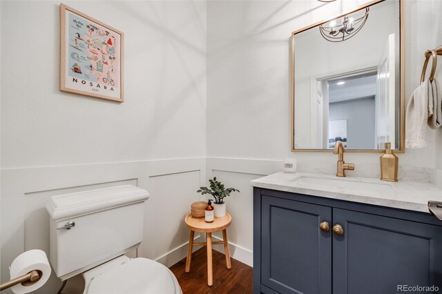 10590 Soulmark Way, Highlands Ranch, CO 80126 - half bath with wainscoting, toilet, wood finished floors, vanity, and a chandelier