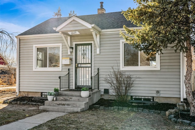 bungalow featuring a chimney and roof with shingles