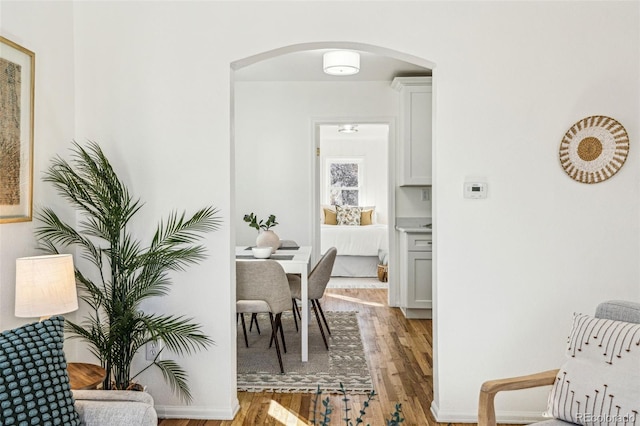 dining area featuring arched walkways and wood finished floors