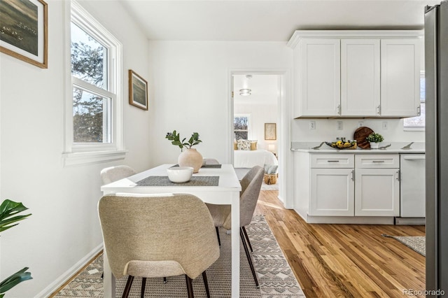 dining space with baseboards and light wood finished floors