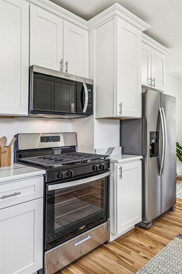 kitchen with light wood-type flooring, appliances with stainless steel finishes, and white cabinets