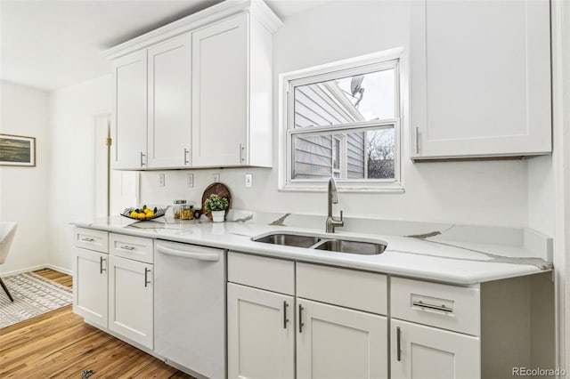 kitchen with light wood-style floors, white cabinets, white dishwasher, a sink, and baseboards