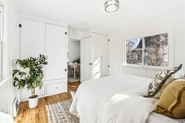 bedroom with visible vents, light wood finished floors, and two closets