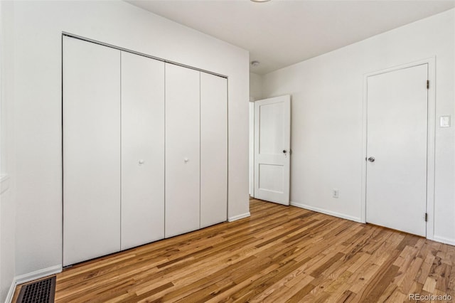 unfurnished bedroom with a closet, light wood-type flooring, and visible vents