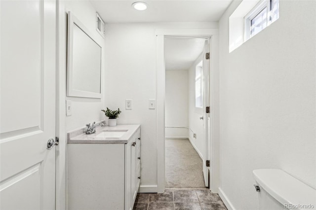 half bathroom featuring baseboards, visible vents, vanity, and toilet