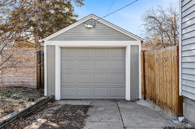 detached garage with concrete driveway and fence