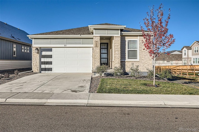 711 N Waterloo Ct, Aurora, CO 80018 - view of front of property featuring fence, driveway, a garage, and stone siding