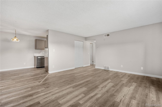 10211 Ura Ln Unit 1-202, Thornton, CO 80260 - unfurnished living room with light wood-style flooring, baseboards, and a textured ceiling