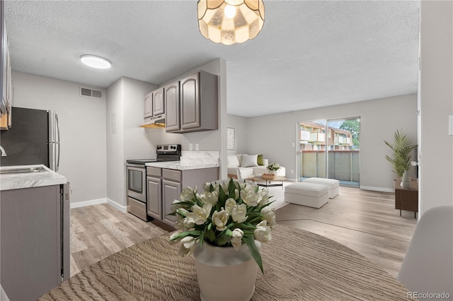 10211 Ura Ln Unit 1-202, Thornton, CO 80260 - kitchen with appliances with stainless steel finishes, gray cabinets, light wood-style floors, under cabinet range hood, and a textured ceiling