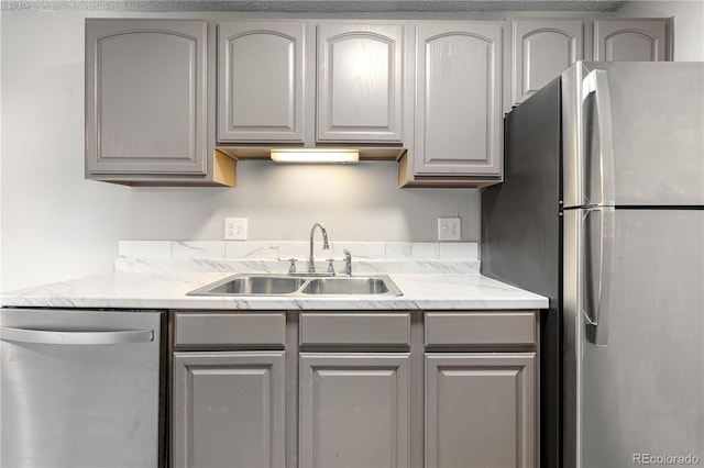 10211 Ura Ln Unit 1-202, Thornton, CO 80260 - kitchen featuring appliances with stainless steel finishes, gray cabinetry, a sink, and light stone countertops