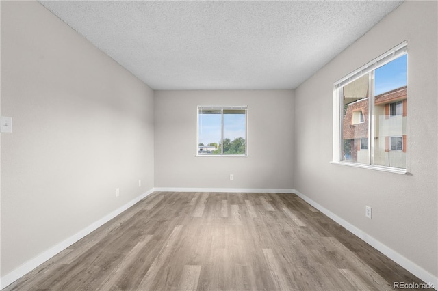 10211 Ura Ln Unit 1-202, Thornton, CO 80260 - spare room with wood finished floors, healthy amount of natural light, a textured ceiling, and baseboards