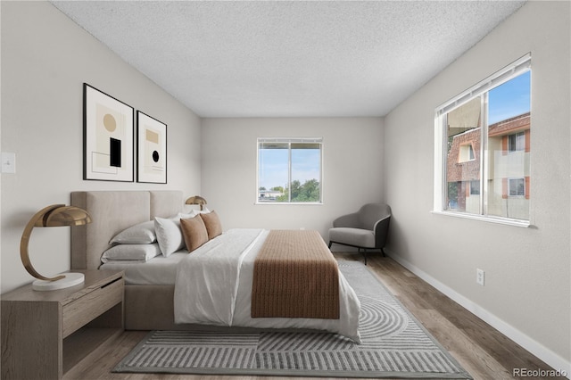 10211 Ura Ln Unit 1-202, Thornton, CO 80260 - bedroom with wood finished floors, a textured ceiling, and baseboards