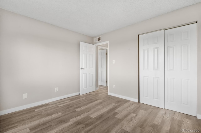 10211 Ura Ln Unit 1-202, Thornton, CO 80260 - unfurnished bedroom featuring wood finished floors, baseboards, a textured ceiling, and a closet